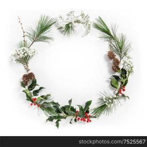 Christmas flat lay. Wreath from pine tree branches with ilex leaves on white background