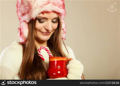 Christmas food concept. Beauty happy girl in winter clothes holding beverage in red mug and cane.. Woman with christmas sweets