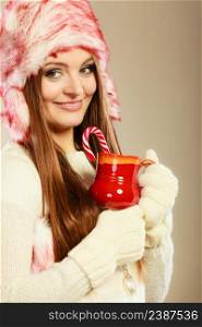 Christmas food concept. Beauty happy girl in winter clothes holding beverage in red mug and cane.. Woman with christmas sweets