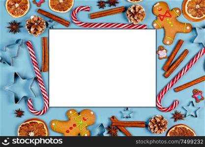 Christmas food frame. Gingerbread cookies, spices and decorations on blue background with blank card for copy space. Christmas food frame