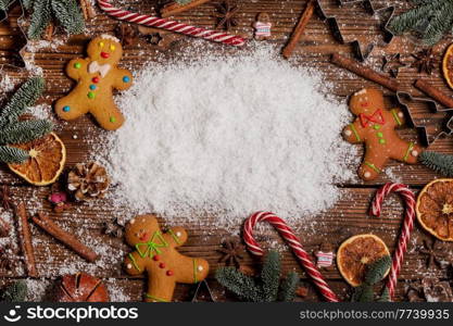 Christmas food frame. Gingerbread cookies, spices and decorations on wooden background with white copy space on snow. Christmas food frame