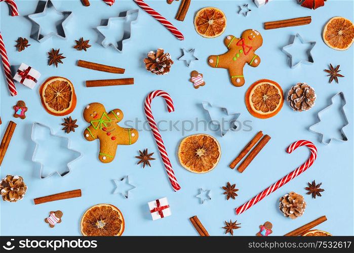 Christmas food gingerbread cookie caramel candy cane cinnamon mold shape anise orange slice and gifts on blue background. Christmas food background