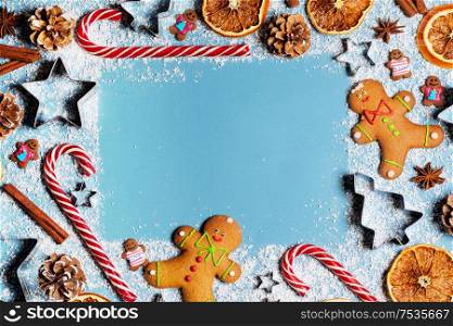 Christmas food gingerbread cookie caramel candy cane cinnamon mold shape anise orange slice on blue background with copy space. Christmas food background