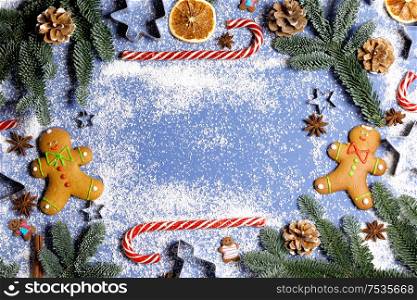 Christmas food gingerbread cookie caramel candy cane cinnamon mold shape anise orange slice and fir tree on blue background with copy space. Christmas food background