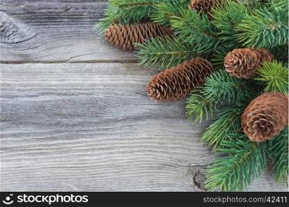 Christmas frame composed of pine cones and spruce branches on the background of old unpainted wooden boards; with copy-space