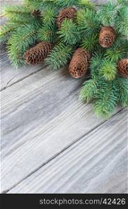 Christmas frame composed of pine cones and spruce branches on the background of old unpainted wooden boards; Christmas composition for greeting card with copy-space