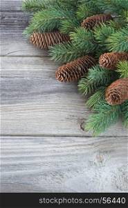 Christmas frame composed of pine cones and spruce branches on the background of old unpainted wooden boards; Christmas composition for greeting card with copy-space. Christmas composition for greeting card