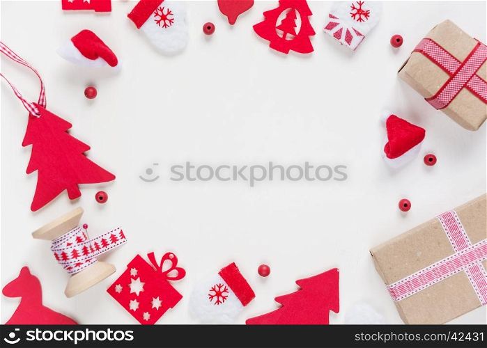 Christmas frame composed of red Christmas decoration: spruce, mittens, Santa's hat, checkered ribbon and gift boxes on white background. Christmas wallpaper for greeting card, websites, social media, business owners, magazines, bloggers, artists etc.