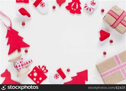 Christmas frame composed of red Christmas decoration: spruce, mittens, Santa's hat, checkered ribbon and gift boxes on white background. Christmas wallpaper for greeting card, websites, social media, business owners, magazines, bloggers, artists etc.