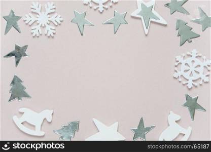 Christmas frame composed of white christmas decoration: snowflakes, stars, Christmas trees and toy; rocking horse on pink background. Flat lay composition for greeting card, websites, social media, magazines, bloggers, artists etc.