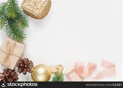 Christmas frame, consisting of fir branches, cones, gift boxes, Christmas golden ball and a pink ribbon on a white background