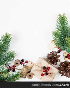 Christmas frame, consisting of fir branches, cones, red holly berries and gift boxe tied with hemp twine on a white background with space for text. Flat lay composition for greeting cards, websites, social media, magazines, bloggers, artists etc. Christmas wallpaper
