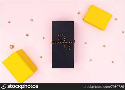 Christmas Gift box, black and yellow present box on pink background. Christmas, winter, new year concept. Flat lay, top view, copy space