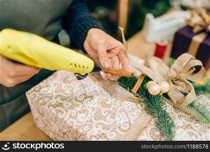 Christmas gift box wrapping and decoration with fir branch. Woman wraps present on the table, decor procedure, festive package