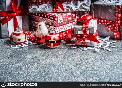 Christmas gift boxes with paper and red ribbons on gray rustic background, side view.