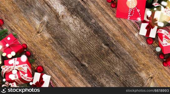 Christmas gift giving concept - christmas presents in red and white boxes on wooden table, flat lay banner with copy space. Christmas gift giving