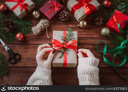 Christmas gift wrapping process. Woman decorates box with a red ribbon.. Christmas gift wrapping process. Woman decorates box with red ribbon.
