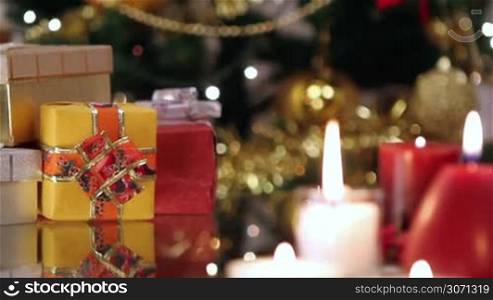 Christmas gifts and candles in front of Christmas tree.