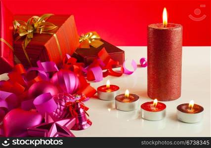 Christmas gifts and four candles over red background