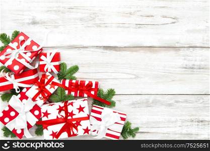 Christmas gifts and pine tree branches on bright wooden background. Festive decoration
