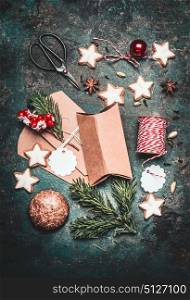 Christmas gifts decoration and making. Festive gift Cardboard boxes, ribbon, fir brunches, cookies and Gingerbread, scissors and Christmas balls on rustic background, top view, flat lay