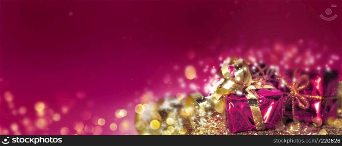 Christmas gifts in golden confetti and blur lights on pink background
