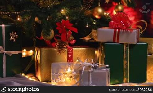Christmas gifts near Christmas tree and fireplace. Christmas gifts in atmospheric lights. Dolly shot