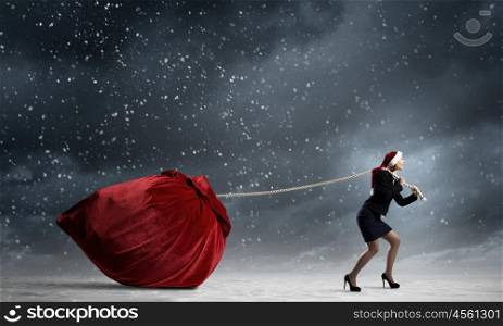 Christmas gifts. Santa woman pulling huge red gifts bag