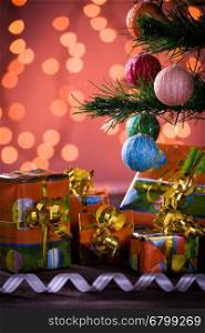 Christmas gifts with blurred lights on background and ribbon under the tree. Christmas gifts with blurred lights and ribbon