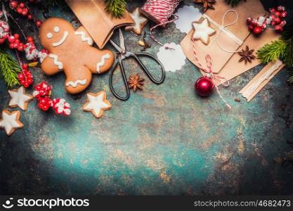 Christmas gifts wrapping with gingerbread man, star cookies, shears and handmade cardboard boxes on vintage background, top view, border
