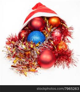 christmas gifts - xmas balls and decorations spill out from red santa hat on white background