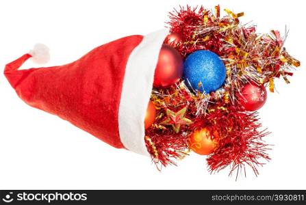 christmas gifts - xmas decorations and tinsel pour out from red santa hat on white background