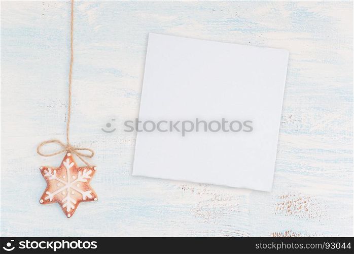 Christmas gingerbread cookie with a pattern in the form of snowflakes and white paper card on the wooden background