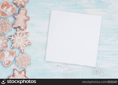 Christmas gingerbread cookies and white paper card on the blue wooden background with copy-space