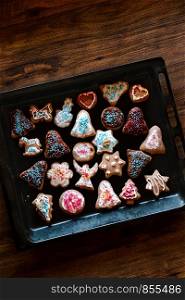 Christmas gingerbread cookies in many shapes decorated with colorful frosting, sprinkle, icing, chocolate coating, toppers, put on tray