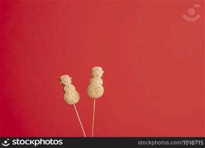 Christmas gingerbread cookies in snowman shape on a stick, on a red background. Xmas famous dessert. Christmas traditional cookies on skewers.
