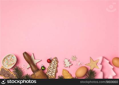 Christmas gingerbread cookies in the shape of a Christmas tree and baking ingredients on pink background