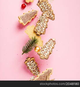 Christmas gingerbread cookies in the shape of a Christmas tree falling or flying in motion against pastel pink background, square composition. Christmas gingerbread cookies in the shape of a Christmas tree falling or flying in motion against pastel pink background