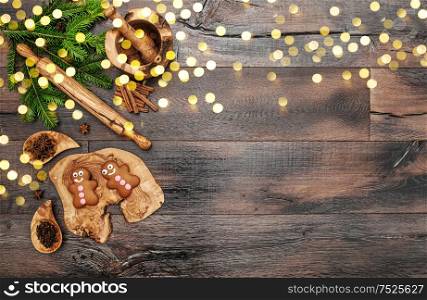 Christmas gingerbread man cookies, spices and baking tools. Holidays food background with golden lights effect