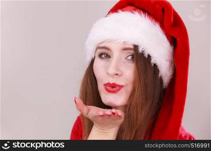 Christmas girl blowing a kiss. Young lady wearing santa claus cap. Celebration holiday happiness concept.. Christmas woman blowing a kiss