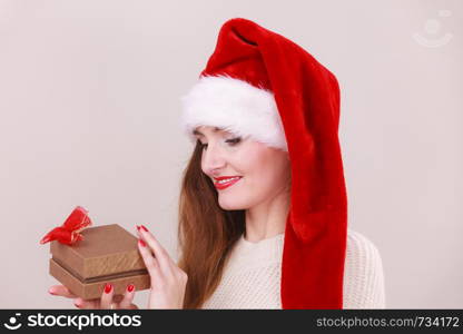 Christmas girl with small gift. Young woman holding ribon box wearing santa cap. Celebration leisure relax holidays concept. . Christmas girl with small gift.