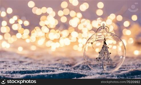 Christmas glass ball with tree in it on winter background. Snow and christmas lights.. Christmas glass ball with tree in it on winter background.