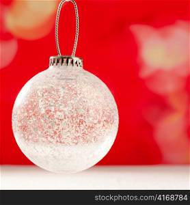 Christmas glass transparent bauble on snow and red background