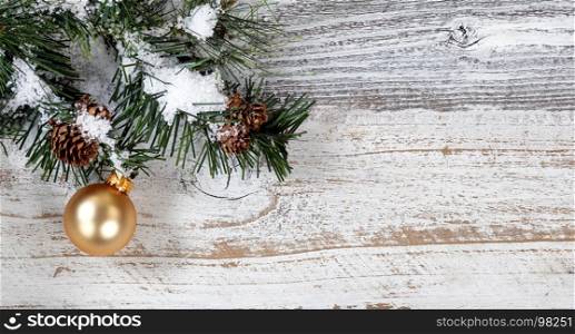 Christmas gold ornament hanging in rough fir tree branch on rustic white wooden background