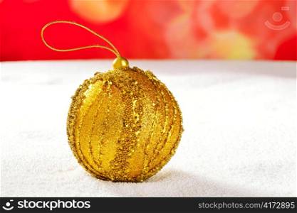 Christmas golden bauble on snow and red background