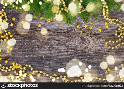 christmas golden decorations and fir tree frame on wooden background with light beams. christmas frame with light beams