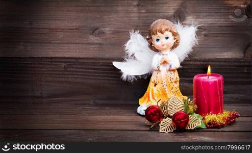 Christmas greeting card with candle and angels on wooden background.