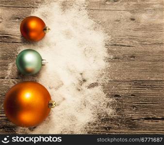 Christmas greeting card with Christmas balls and snow on a wooden background.. Christmas greeting card with Christmas balls and snow on a wooden background