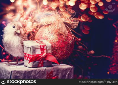 Christmas greeting card with gift boxes, decoration ball and bird at festive bokeh lighting background
