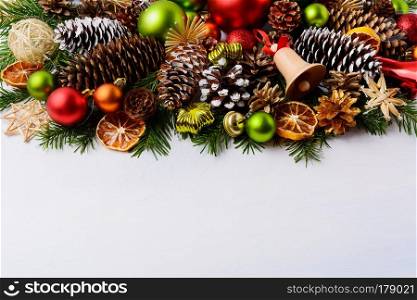 Christmas greeting card with pine cones and wooden jingle bell. Christmas decoration with baubles, handmade straw ornaments and dried orange slices.  Copy space.